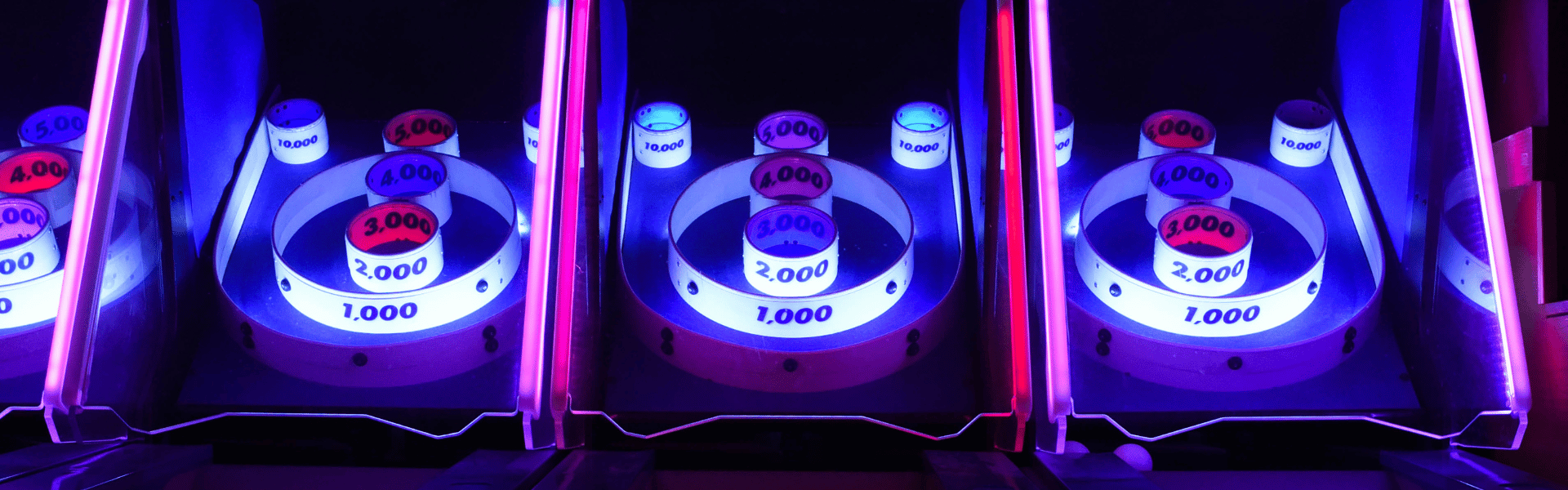 Colorful arcade games with neon lighting and point values